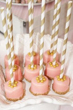 there are many pink and gold desserts with straws on the sticks in front of them