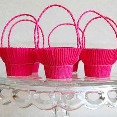 three pink baskets sitting on top of a glass shelf