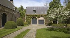 a large house with two garages in front of it and landscaping around the entrance