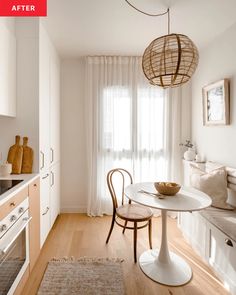 a white kitchen with a table and chairs in the center, next to an oven