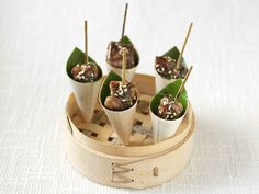 small food items are placed on sticks in a bamboo container