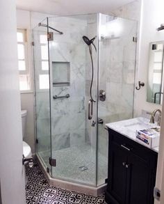 a bathroom with a walk in shower next to a white toilet and black cabinetry