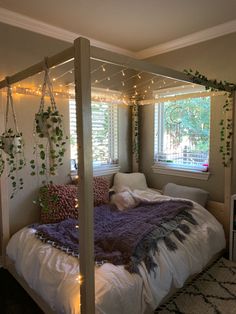 a bed with white sheets and lights on the headboard is in front of a window