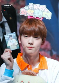 a young man holding up an item in front of his face and another person behind him