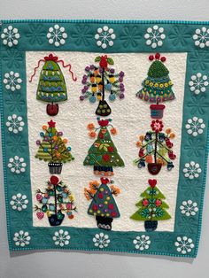 a quilted wall hanging with christmas trees on it