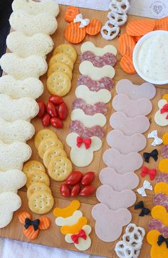 a wooden cutting board topped with lots of different types of crackers and cheeses