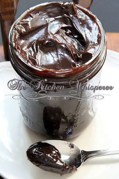 a spoon is sitting on a white plate next to a jar of chocolate cake pudding