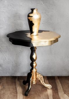 a black and gold table with a vase on top