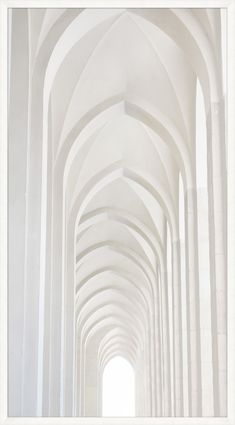 an image of a long hallway that is white and has arches on the ceiling with light coming through