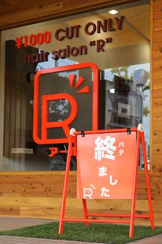 an orange sign sitting in front of a building with chinese writing on it's side