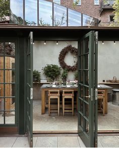 an outdoor dining area with sliding glass doors leading to the patio and covered in greenery