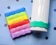 three plastic name tags sitting on top of a blue surface next to a white cup