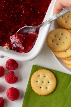 raspberry sauce being spooned into crackers with raspberries on the side