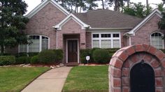 a brick house with a mailbox in front of it and trees around the door