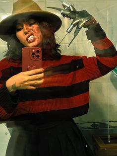 a woman wearing a hat taking a selfie in the mirror with her cell phone