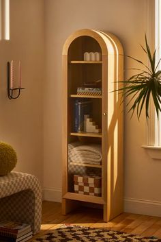 a wooden shelf with books and baskets on it next to a window in a living room