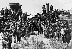 a group of men standing next to each other in front of a train on tracks