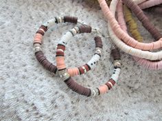 three bracelets are laying on the floor next to each other and one is made out of wood beads