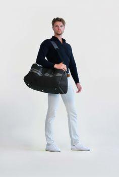 a man holding a large black bag in his hand while standing against a white background