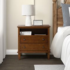 a bedroom with a bed, night stand and lamp on the nightstand next to it