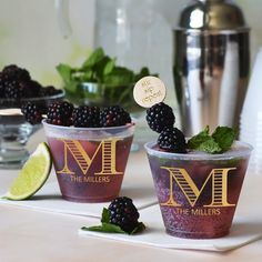 two cups filled with blackberries on top of a table