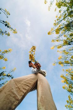 a man reaching up into the sky with his hands in the air while standing between two tall trees