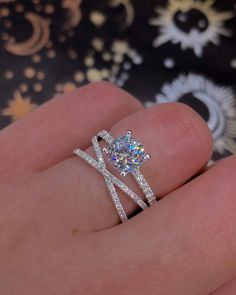 a woman's hand with a diamond ring on top of her finger and an engagement band