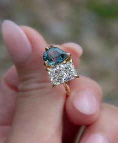 a person holding a ring with a blue stone in it