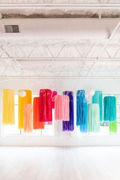 colorful streamers hang from the ceiling in an empty room with white walls and exposed ceilings