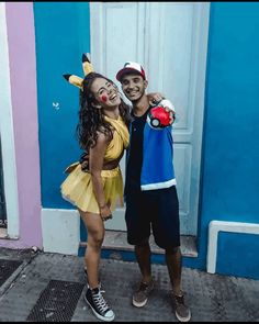 two people standing in front of a blue building with one person holding a stuffed animal