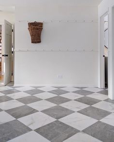 an empty room with a checkered floor and basket hanging on the wall