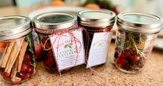 four mason jars filled with cherries and cinnamon sticks