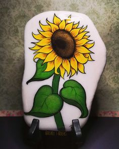 a sunflower painted on the side of a white toilet