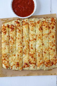 several flat breads on a cutting board next to a bowl of ketchup