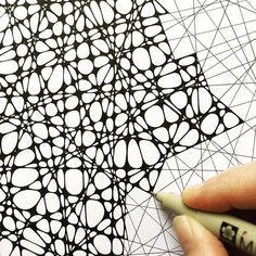 someone is drawing an intricate pattern on paper with a marker and pen, while the image appears to be in color