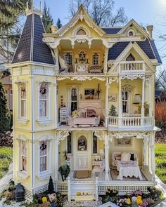 a doll house is shown in the middle of a yard with flowers and trees around it