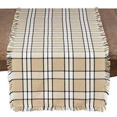 a plaid table runner on top of a wooden table with a white and black checkered blanket