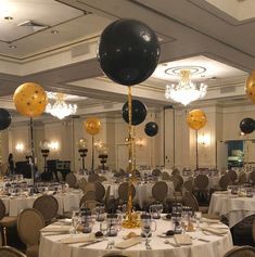 a room filled with lots of tables covered in white tablecloths and black balloons