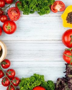 tomatoes, lettuce and other vegetables arranged in a circle on a white wooden surface