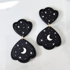 two black earrings with white stars and moon designs