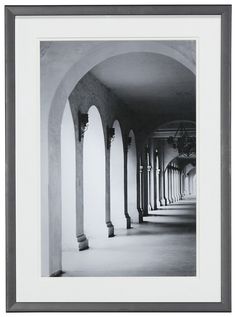 black and white photograph of an archway in a building with columns on both sides, looking into the distance