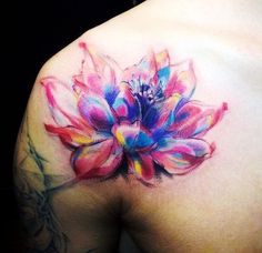 a colorful flower tattoo on the back of a woman's shoulder