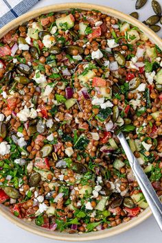 a bowl filled with lentils, tomatoes, cucumbers and feta cheese