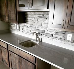 a kitchen counter top with a sink and wooden cabinets in front of the countertop