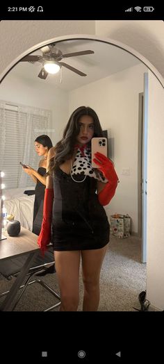 a woman taking a selfie in front of a mirror with her cell phone and red gloves