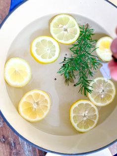 lemons and herbs are in a pan with water