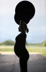 a pregnant woman lifting a large object over her head