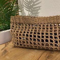 a crocheted purse sitting on top of a wooden table next to a potted plant