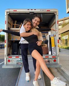 a man and woman sitting in the back of a moving truck with their arms around each other