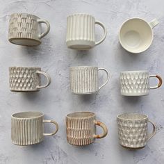 nine white cups and saucers lined up on a gray surface with one cup in the middle